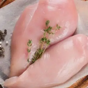 Pasture raised and Certified Organic Chicken Breasts from Wrong Direction Farm on a ceramic plate with herbs.