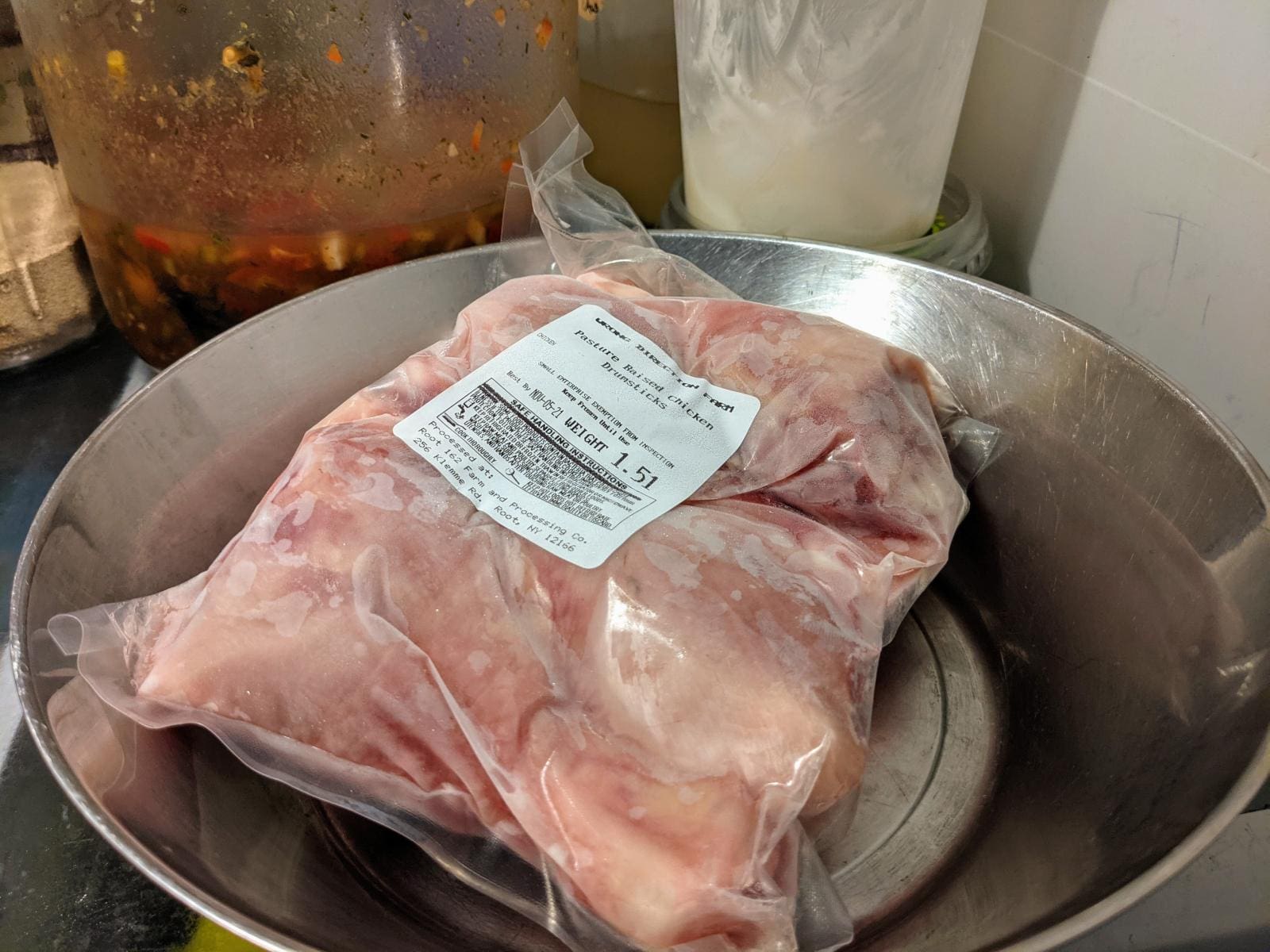 Pasture raised chicken defrosting in the refrigerator. The package is placed on a bowl to catch any drips.