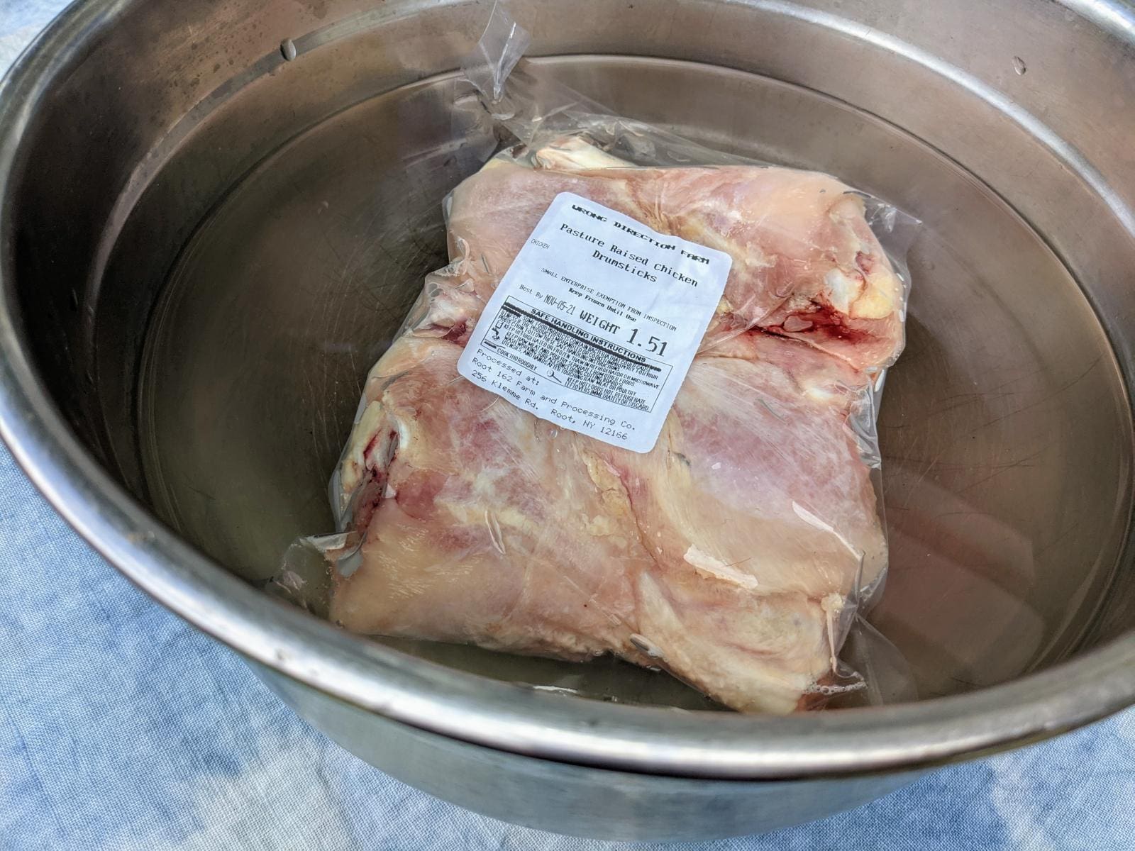To save time, this image shows a package of pasture raised chicken defrosting submerged in a bowl of water as it is about to be placed in the refrigerator.
