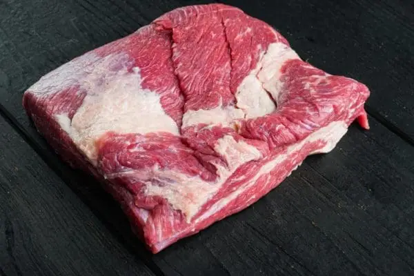 Raw grass fed beef brisket on slate background.