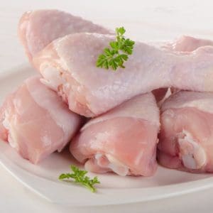 Pasture raised and Certified Organic Raw Chicken Drumsticks from Wrong Direction Farm on a white plate.