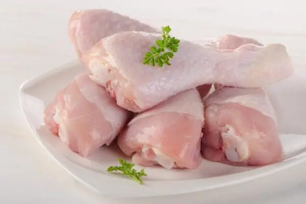 Pasture raised and Certified Organic Raw Chicken Drumsticks from Wrong Direction Farm on a white plate.