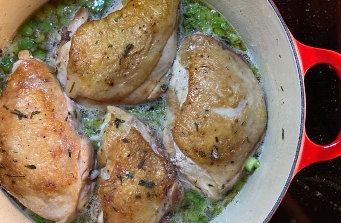 Certified organic pasture raised Chicken thighs from Wrong Direction Farm cooking in braising dish with cider and leeks