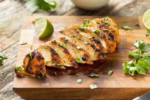 Pasture raised and Certified Organic Grilled Chicken Breast from Wrong Direction Farm with chipotle and lime on a wooden cutting board.