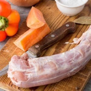 Pasture raised, Certified Organic turkey neck from Wrong Direction Farm on a cutting board with vegetables.
