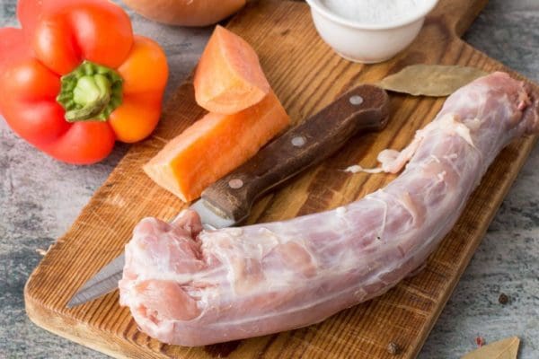 Pasture raised, Certified Organic turkey neck from Wrong Direction Farm on a cutting board with vegetables.