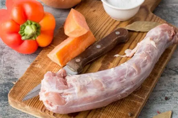 Pasture raised, Certified Organic turkey neck from Wrong Direction Farm on a cutting board with vegetables.