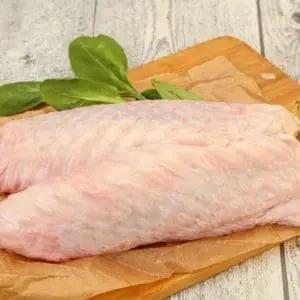 Raw pasture raised turkey wings from Wrong Direction Farm. Photo with two wings sitting on a cutting board.