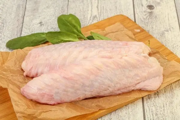 Raw pasture raised turkey wings from Wrong Direction Farm. Photo with two wings sitting on a cutting board.