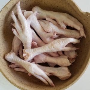 Pasture raised and Certified Organic chicken feet from Wrong Direction Farm in a ceramic bowl.