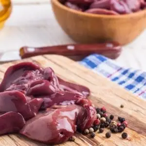 Pasture raised and Certified Organic Raw Chicken Livers from Wrong Direction Farm on a wooden cutting board with peppercorns.