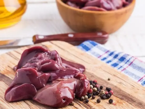 Pasture raised and Certified Organic Raw Chicken Livers from Wrong Direction Farm on a wooden cutting board with peppercorns.