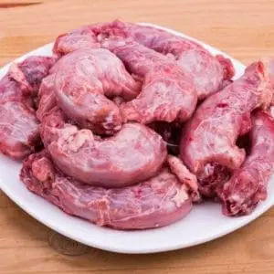 Certified Organic and Pasture Raised chicken necks from Wrong Direction Farm. Neck are shown raw and placed on a white plate.