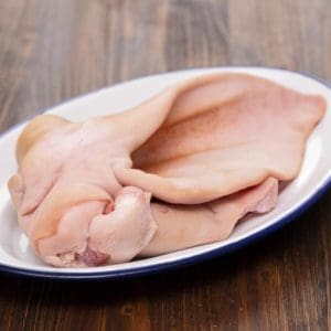 Pasture raised pork ear in bowl on wood cutting board.