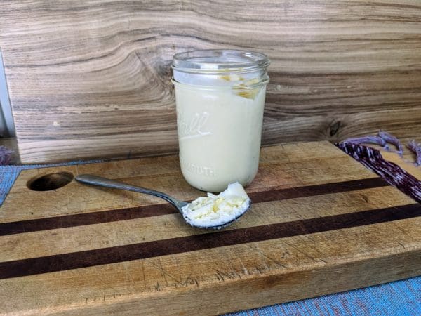 Grass fed tallow from Wrong Direction Farm placed on a cutting board shown next to a jar of tallow.