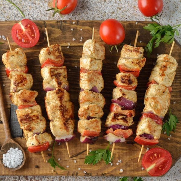 Certified Organic, Pasture Raised Turkey Kabobs from Wrong Direction Farm on a cutting board with tomatoes, parsley, and salt.