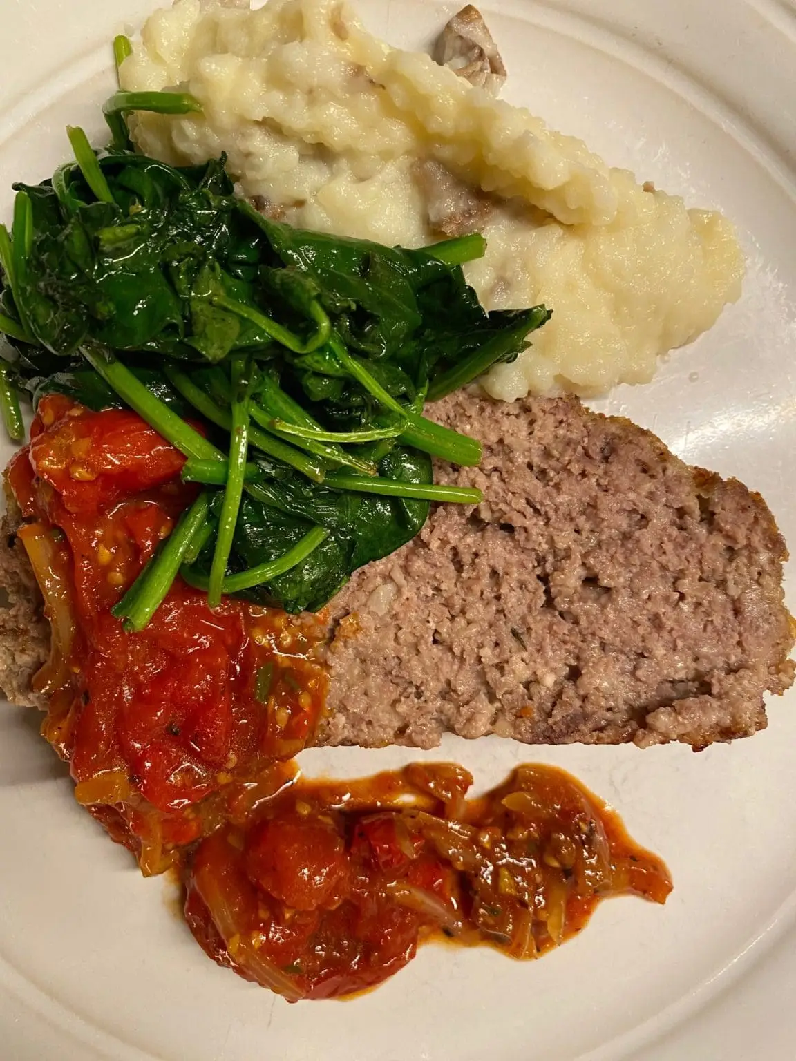 Grass fed beef meatloaf with tomato relish on a plate.