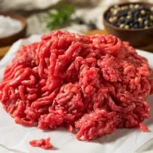 Lean grass fed ground beef on a table with salt and pepper