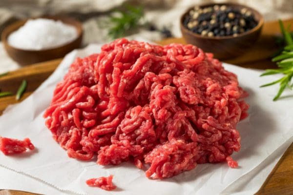 Lean grass fed ground beef on a table with salt and pepper