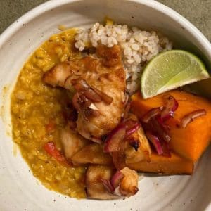 A bowl of miso butter chicken, made with Certified Organic, pasture raised chicken breasts from Wrong Direction Farm. Served with sweet potatoes, rice, lentils, and pickled onions,