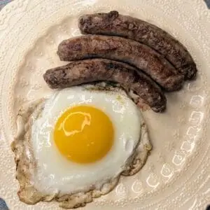 Grass fed beef breakfast sausage links on a plate with a sunny side up egg.