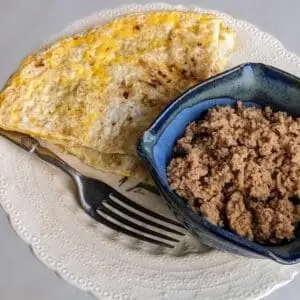 Cooked pasture raised chicken chorizo sausage in a handmade bowl served along with an omelet.