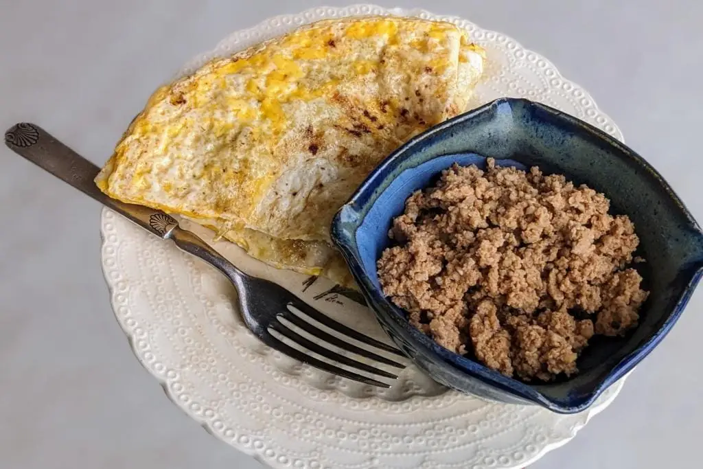 Cooked pasture raised chicken chorizo sausage in a handmade bowl served along with an omelet.