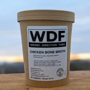 One container of Wrong Direction Farm bone broth on a cutting board with a sunrise sky in the background.