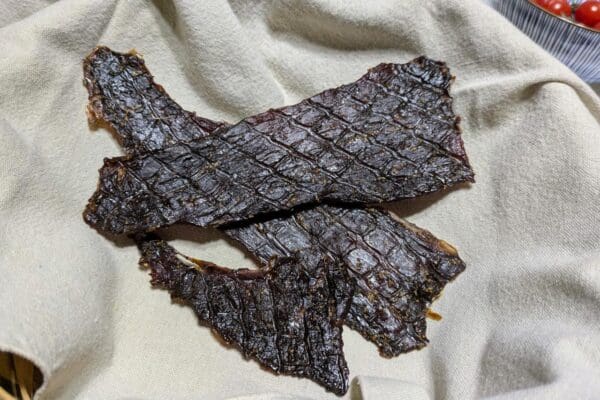 Grass Fed Beef Jerky from Wrong Direction Farm photographed on a linen cloth in a basket.